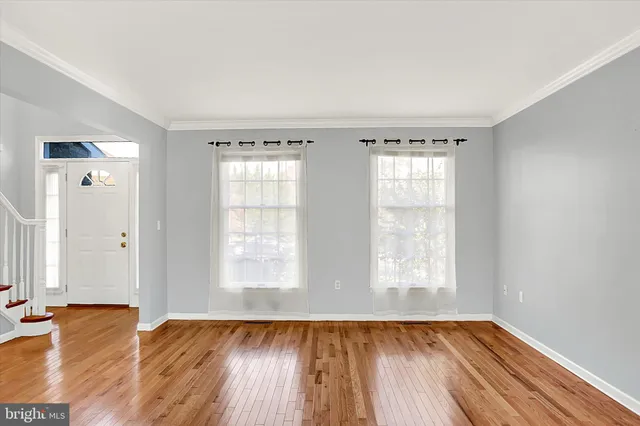 a view of an empty room with wooden floor and stairs