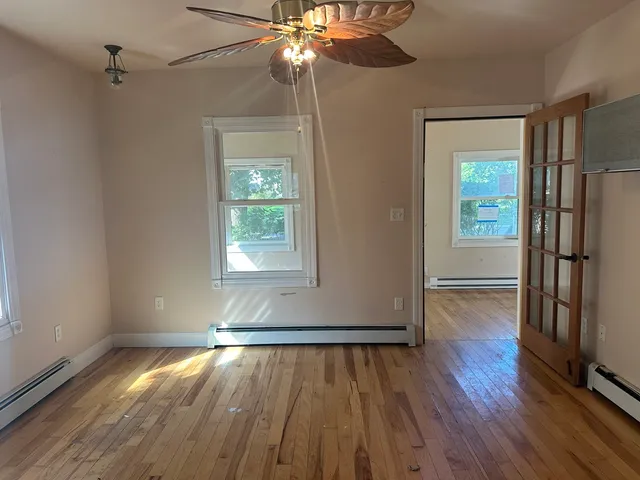 a view of empty room with wooden floor and fan