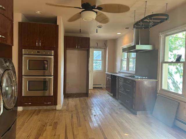 a kitchen with stainless steel appliances granite countertop a refrigerator a sink dishwasher a stove and a dining table with wooden floor