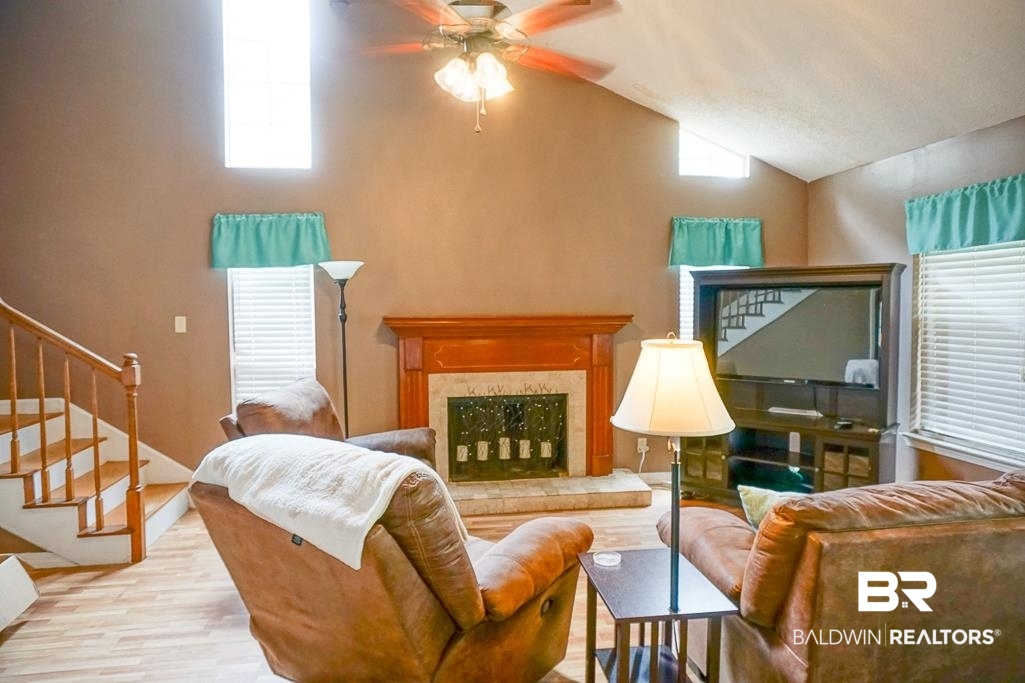 254 Thrift Street Mobile, AL 36609 - Photo 3 of 16 Living area featuring a fireplace, wood finished floors, stairs, lofted ceiling, and ceiling fan
