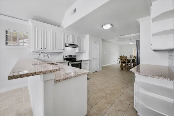 a kitchen with granite countertop a sink a stove and a refrigerator