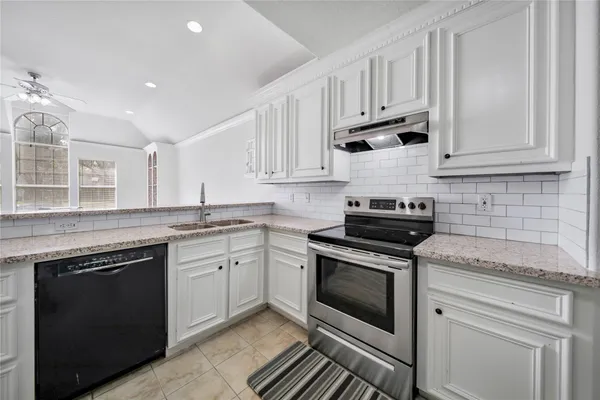 a kitchen with granite countertop white cabinets and appliances