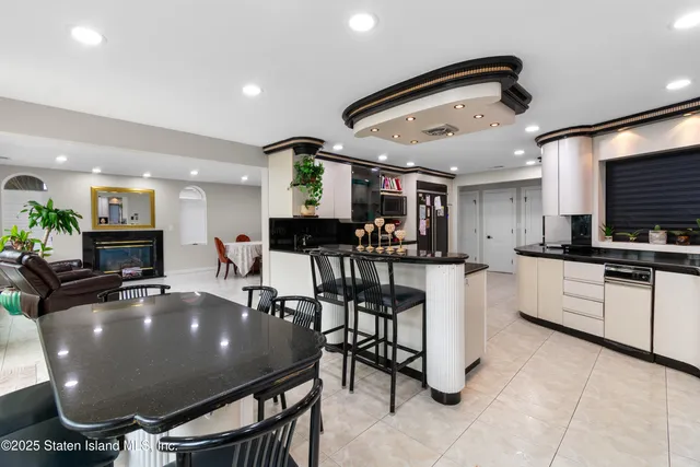 a kitchen with stainless steel appliances kitchen island granite countertop a table chairs sink and cabinets