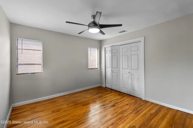 a view of empty room with wooden floor and fan