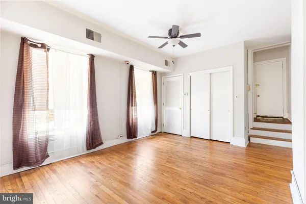 a view of empty room with wooden floor and fan