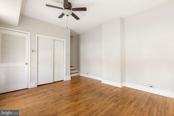 an empty room with wooden floor ceiling fan and windows
