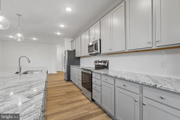a kitchen with granite countertop white cabinets and stainless steel appliances