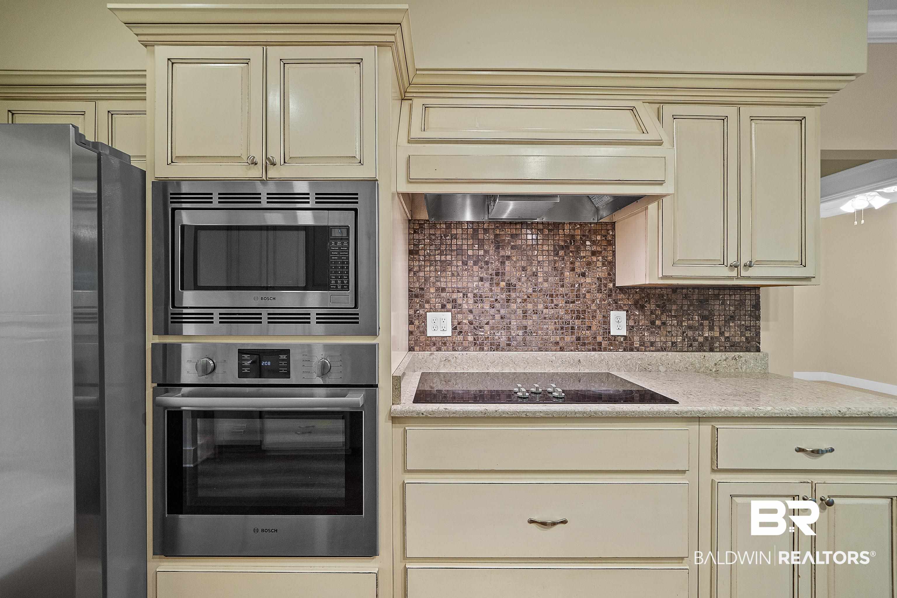 356 Liberty Street Fairhope, AL 36532 - Photo 10 of 39 Kitchen with cream cabinets, stainless steel appliances, tasteful backsplash, light stone countertops, and premium range hood