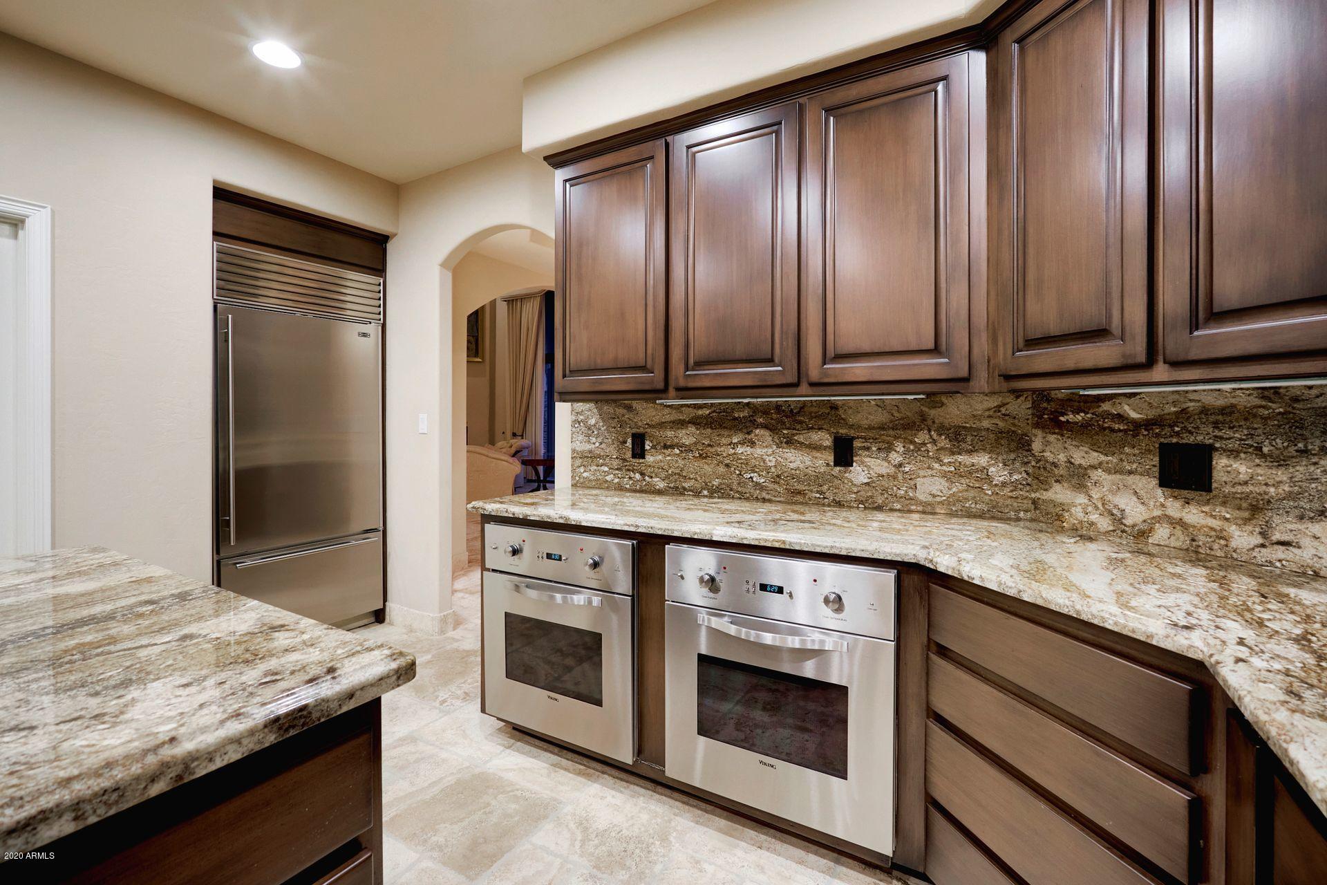 7323 East Gainey Ranch Road, Unit 4 Scottsdale, AZ 85258 - Photo 18 of 56 a kitchen with granite countertop stainless steel appliances and wooden cabinets