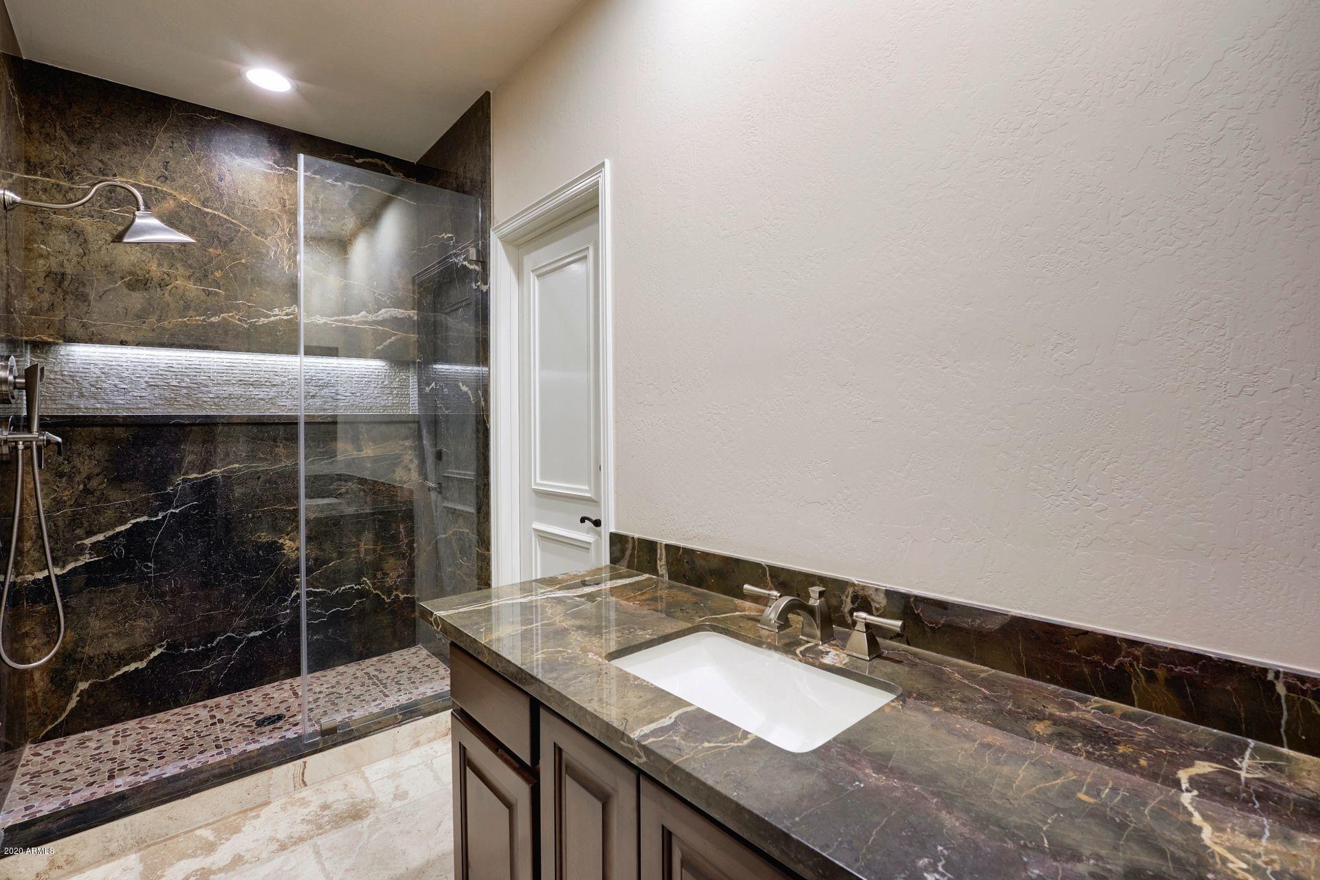 7323 East Gainey Ranch Road, Unit 4 Scottsdale, AZ 85258 - Photo 27 of 56 a bathroom with a granite countertop sink a mirror and shower