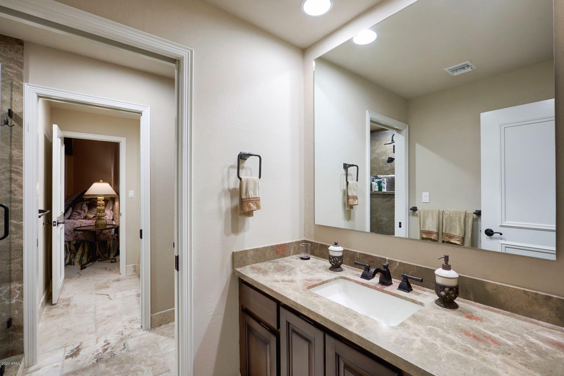 7323 East Gainey Ranch Road, Unit 4 Scottsdale, AZ 85258 - Photo 38 of 56 a en suite bathroom with a granite countertop sink and a mirror
