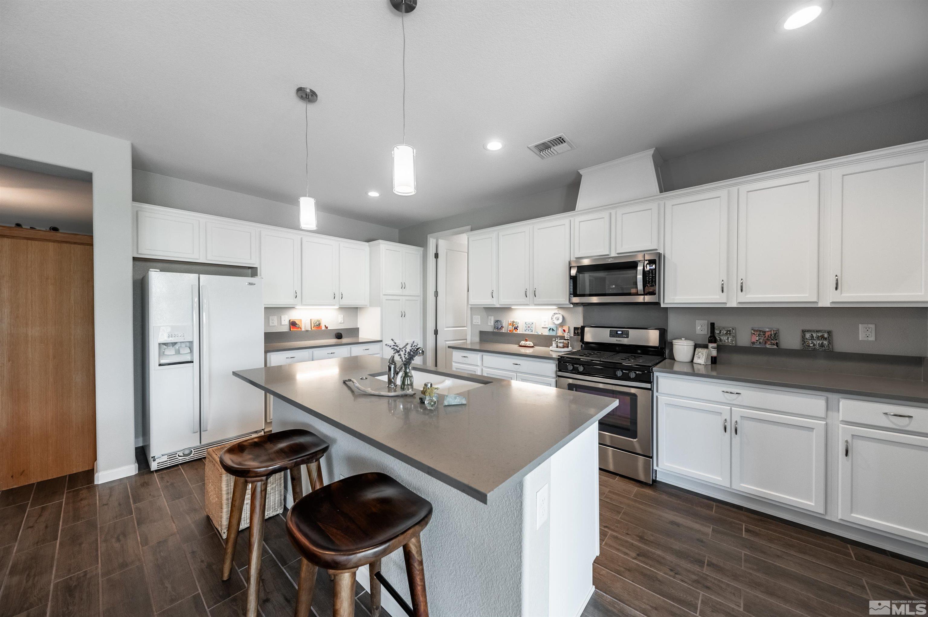 9566 Gazala Lane Reno, NV 89521 - Photo 10 of 40 a kitchen with stainless steel appliances granite countertop a sink a stove a refrigerator cabinets and chairs