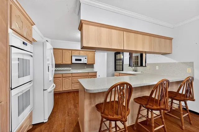 a kitchen with granite countertop a stove a sink and white cabinets with wooden floor