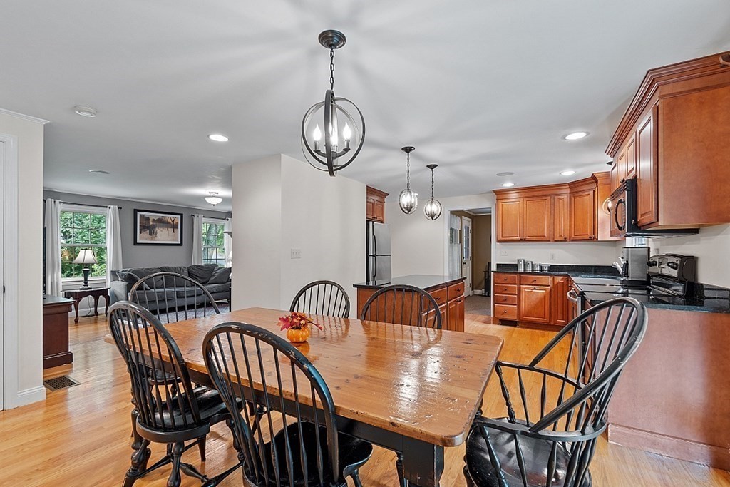 76 Wheeler Road Stow, MA 01775 - Photo 8 of 31 a view of a dining room and livingroom with furniture wooden floor a rug a painting and a chandelier