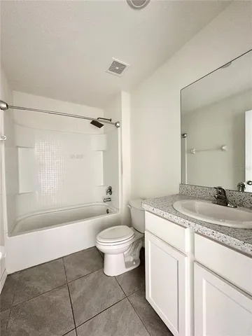 a bathroom with a granite countertop sink a toilet a mirror and bathtub