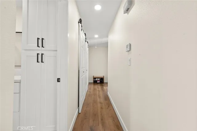 a view of a hallway with wooden floor and a bathroom