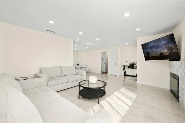 a living room with furniture a flat screen tv and a view of kitchen