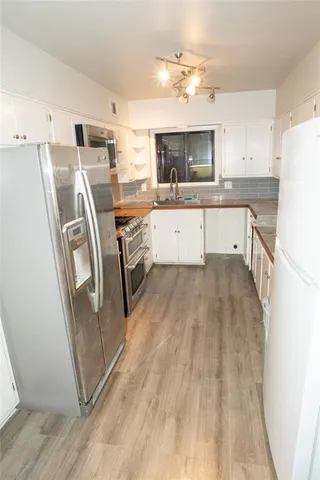a view of a kitchen with fridge and wooden floor
