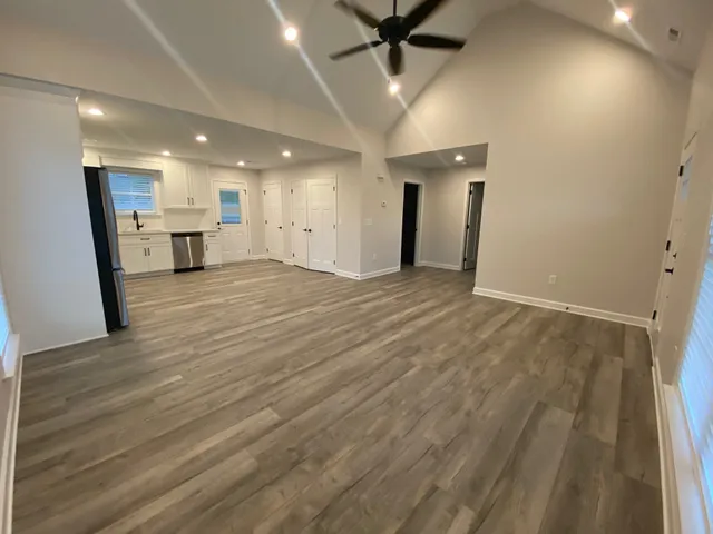 an empty room with wooden floor and a hallway