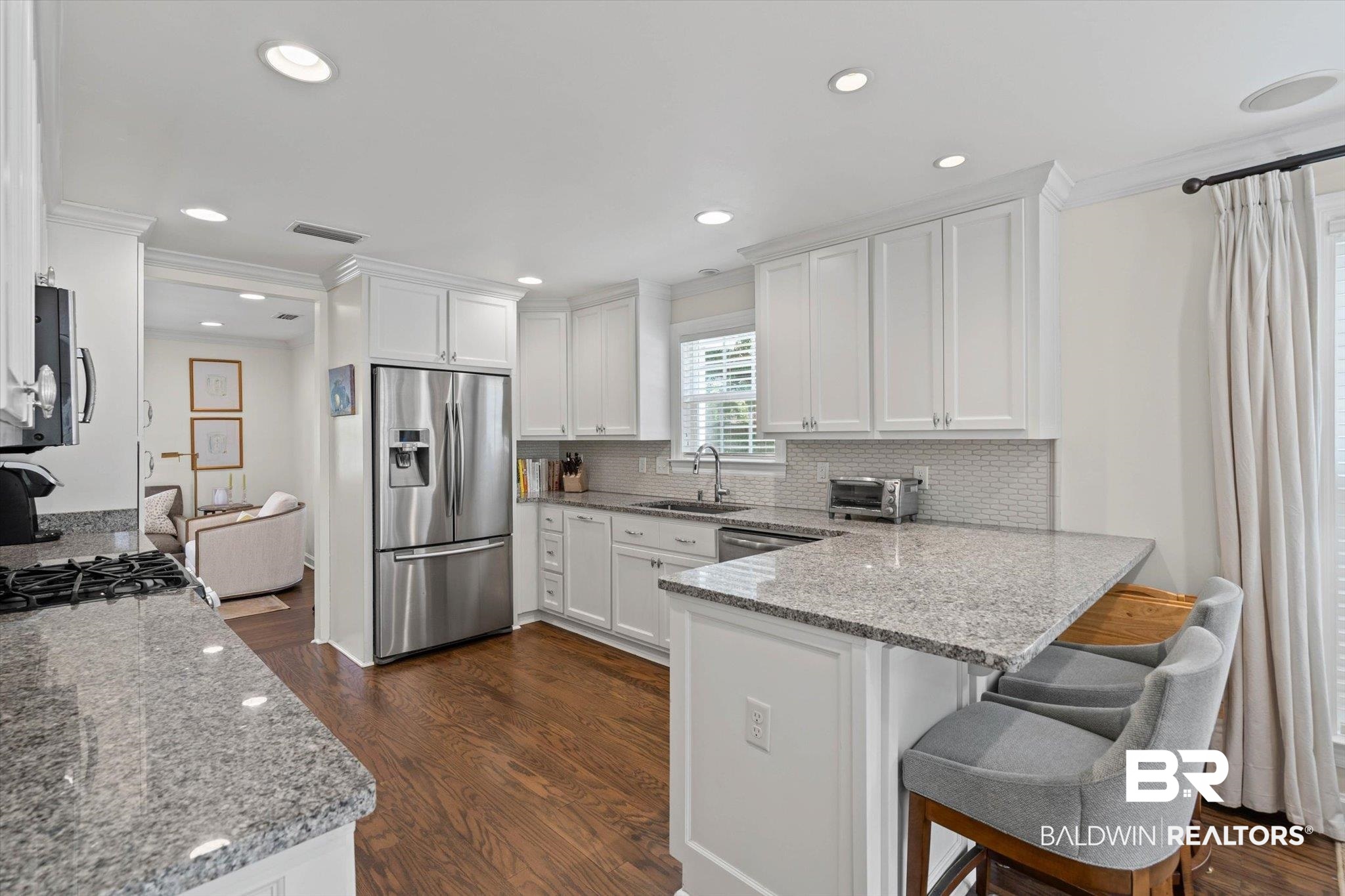 77 North Hathaway Road Mobile, AL 36608 - Photo 10 of 33 Kitchen with light stone countertops, a peninsula, dark wood-style flooring, appliances with stainless steel finishes, and ornamental molding