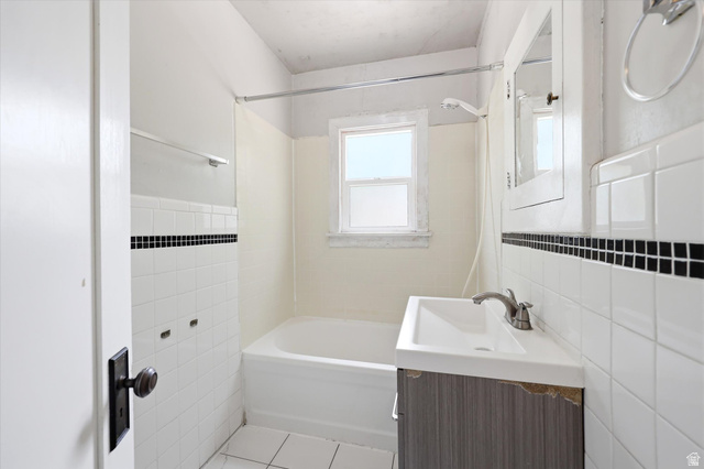 262 West 400 South Springville, UT 84663 - Photo 12 of 17 Bathroom featuring a white bathtub, ceramic wall tiling with a black accent strip, and a window