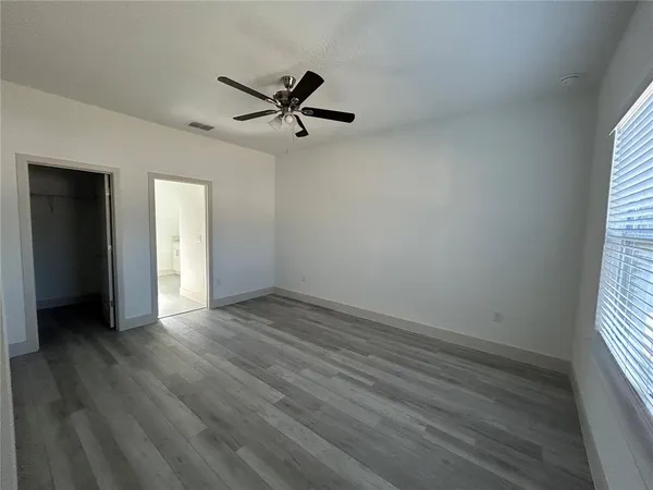 an empty room with wooden floor closet and windows