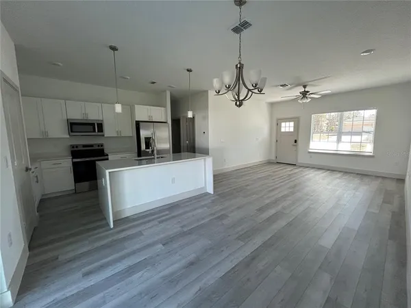 a view of a kitchen with a sink a refrigerator a ceiling fan and wooden floor