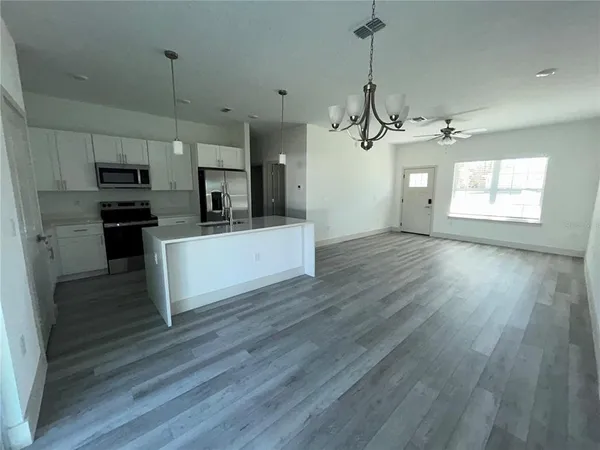 a view of a kitchen with a sink wooden cabinet and stainless steel appliances