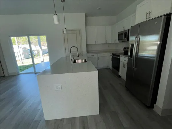 a kitchen with sink a refrigerator and wooden floor
