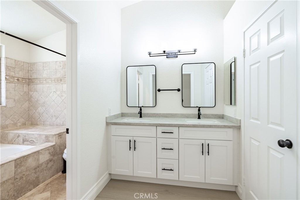 8 Massier Lane Lake Forest, CA 92610 - Photo 17 of 34 a bathroom with a double vanity sink a mirror and a bathtub