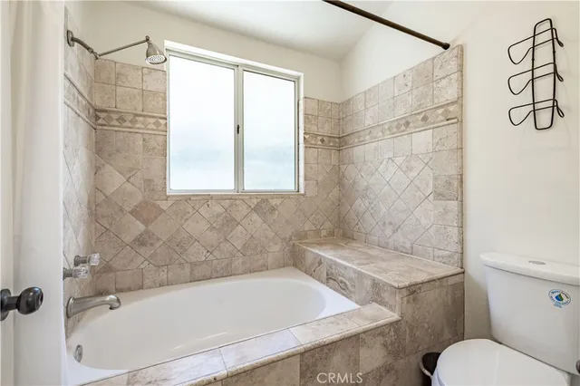 a bathroom with a granite countertop bathtub shower and toilet