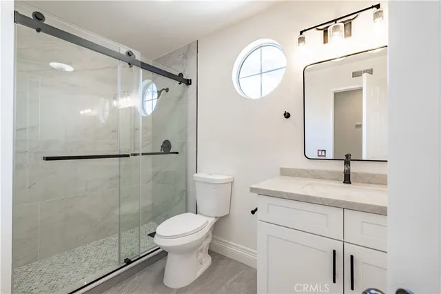 a bathroom with a granite countertop sink mirror toilet and shower