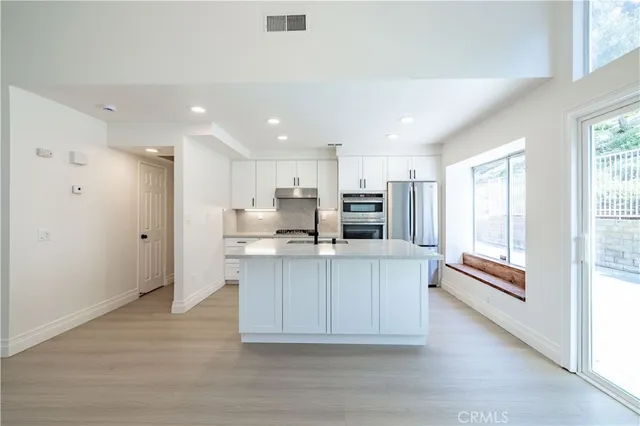 a kitchen with stainless steel appliances granite countertop a refrigerator a sink a stove a microwave and island