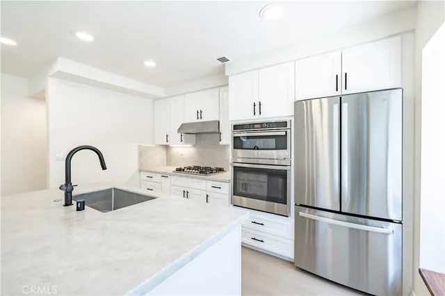 a kitchen with stainless steel appliances a refrigerator sink and stove