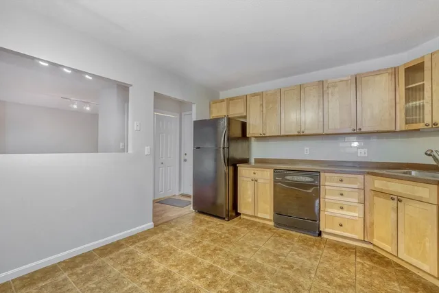 a kitchen with granite countertop a refrigerator and cabinets