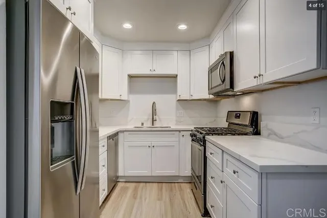 a kitchen with stainless steel appliances granite countertop a refrigerator sink and white cabinets