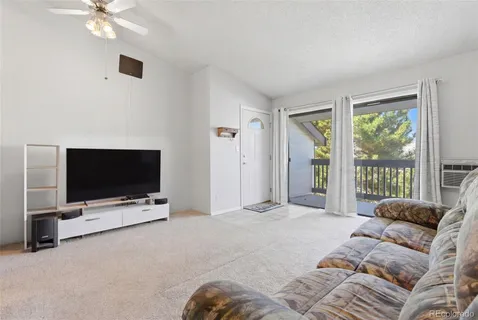 a living room with furniture a flat screen tv and a large window