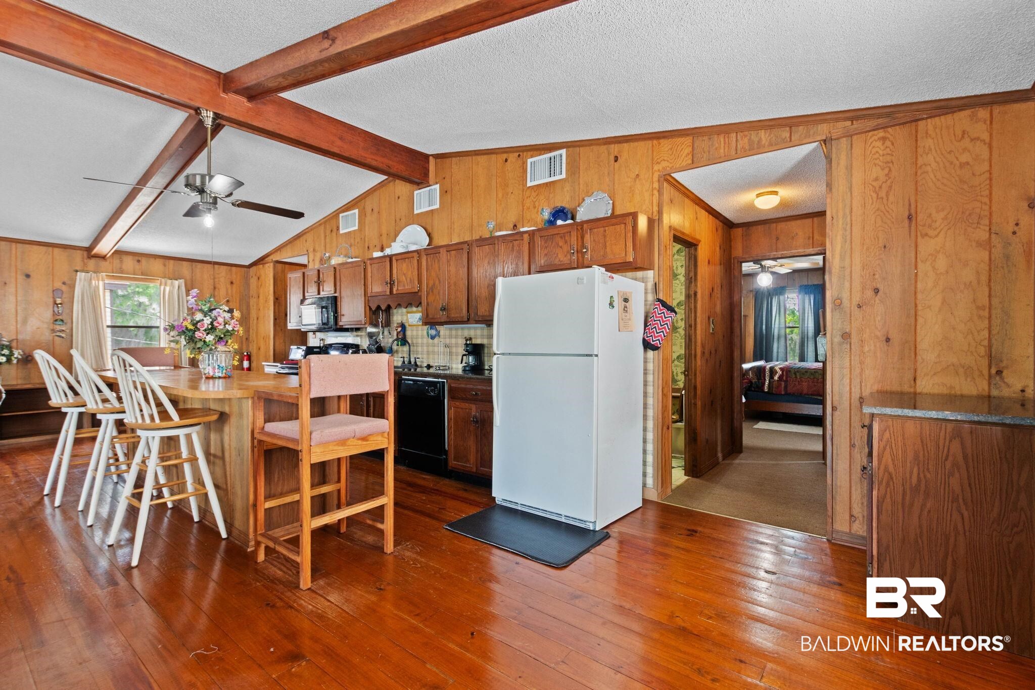 8153 Bryant's Lndg Road Stockton, AL 36579 - Photo 27 of 87 Open-concept kitchen and dining area featuring wood-finish walls and flooring, vaulted ceilings with exposed wood beams, a ceiling fan, and wood cabinetry