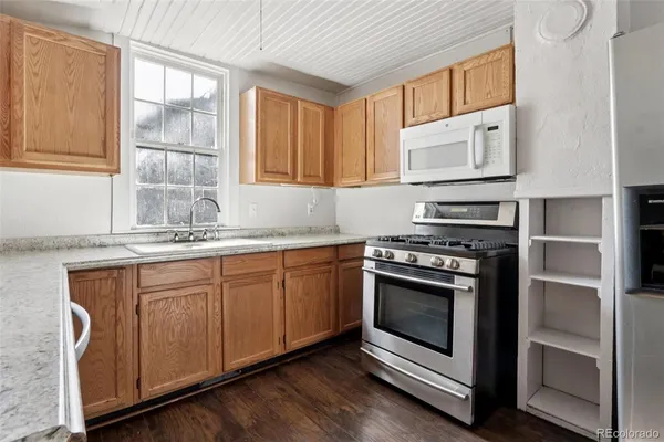 a kitchen with granite countertop stainless steel appliances a stove sink and cabinets