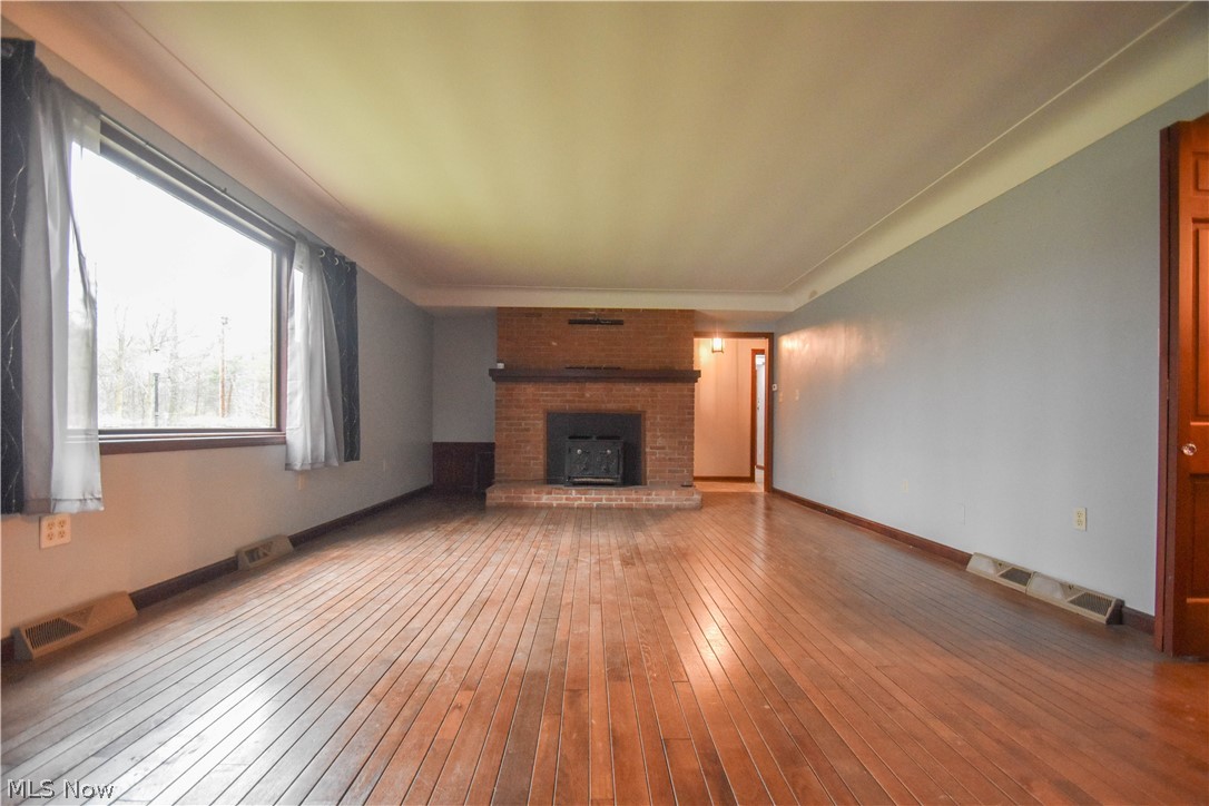 9506 Kirk Road North Jackson, OH 44451 - Photo 15 of 50 Unfurnished living room featuring brick wall, dark wood-type flooring, and a brick fireplace