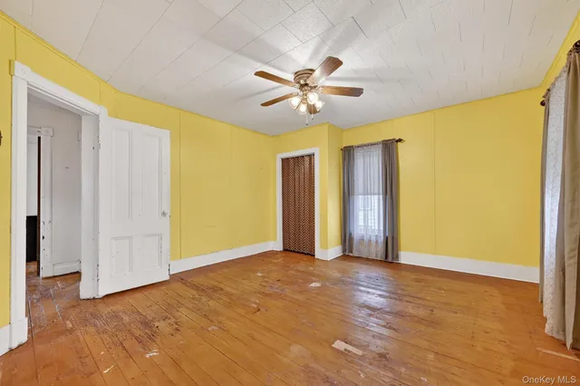 a view of an empty room with chandelier fan and a window