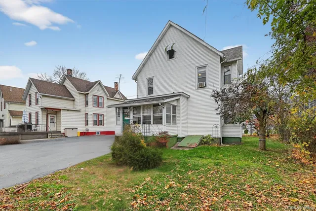 a view of a white house with a big yard and large trees