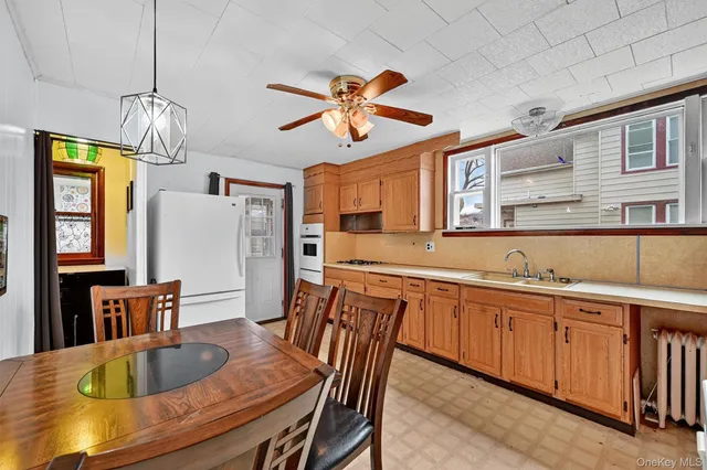 a dining room with stainless steel appliances granite countertop a dining table chairs and a chandelier