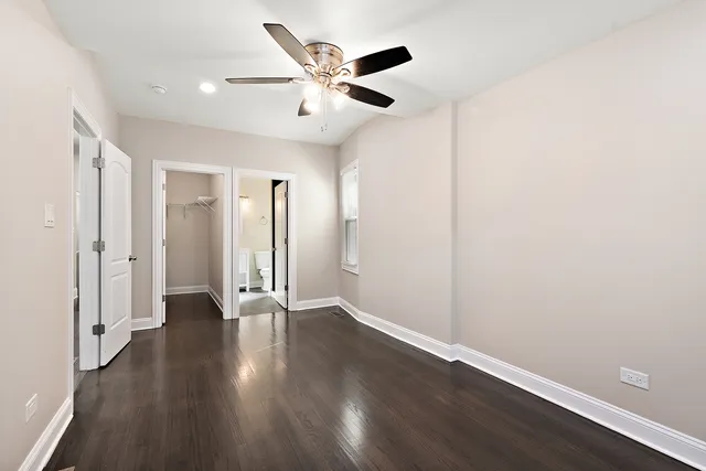 an empty room with wooden floor and a ceiling fan