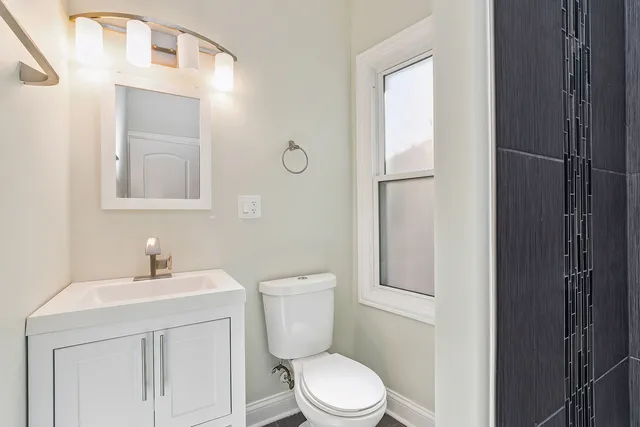 a bathroom with a toilet a sink a vanity and mirror