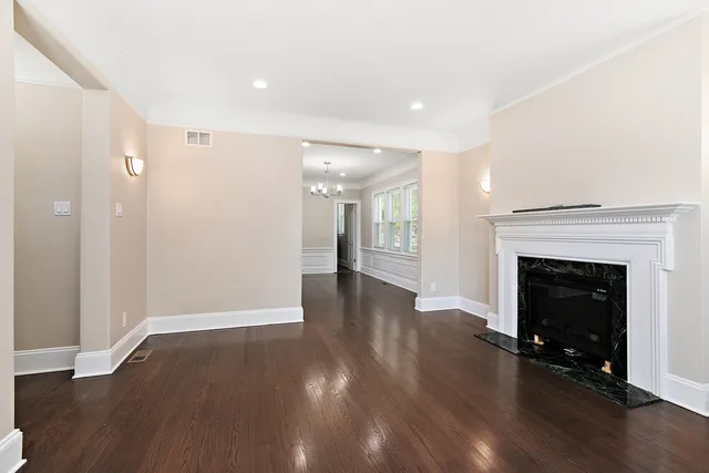 a view of an empty room with wooden floor and a fireplace