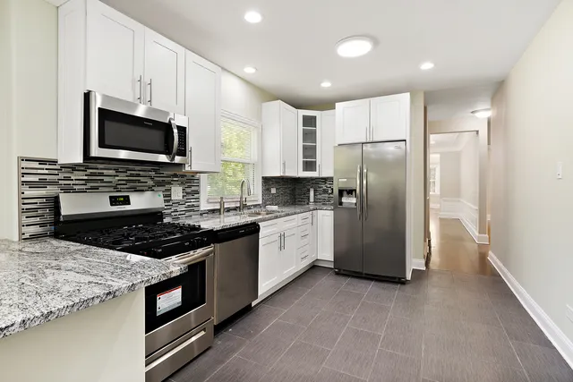 a kitchen with stainless steel appliances granite countertop a stove refrigerator and microwave