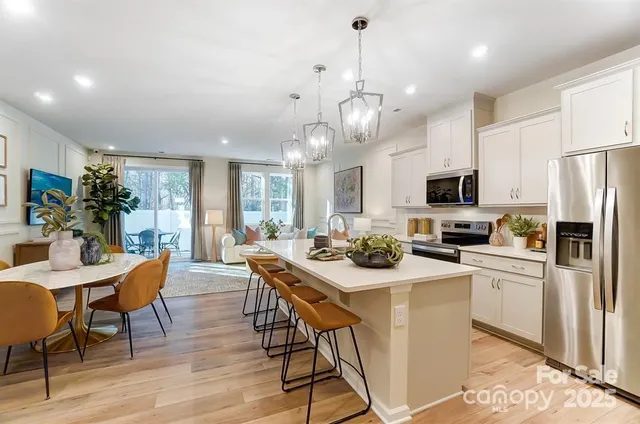 a view of a dining room with furniture a kitchen and chandelier