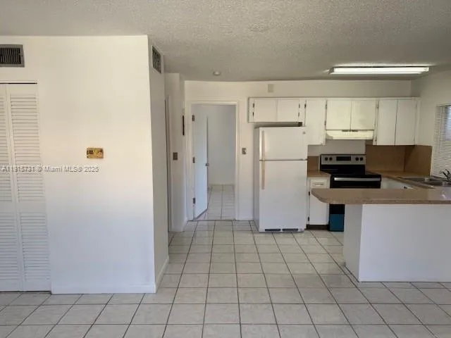 a kitchen with a refrigerator a stove top oven and white cabinets