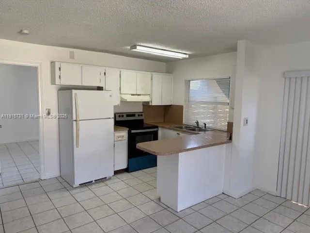 a kitchen with white cabinets and refrigerator